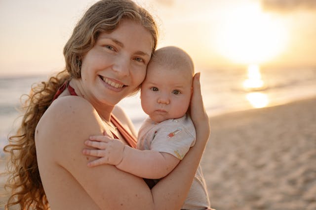 gulf-shores-mom-baby-sunset A mom and baby posing for a picture on a Gulf Shore beach at sunset.